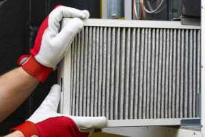 Gloved hand holding an air filter for a furnace