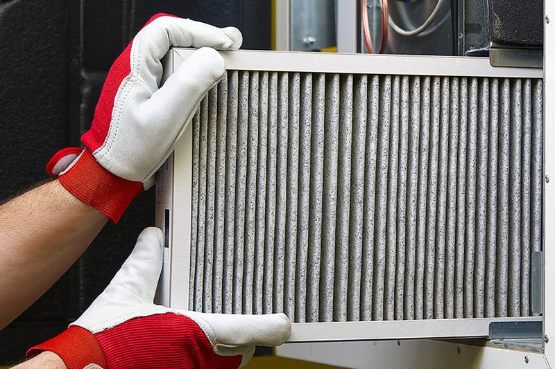 Gloved hand holding an air filter for a furnace