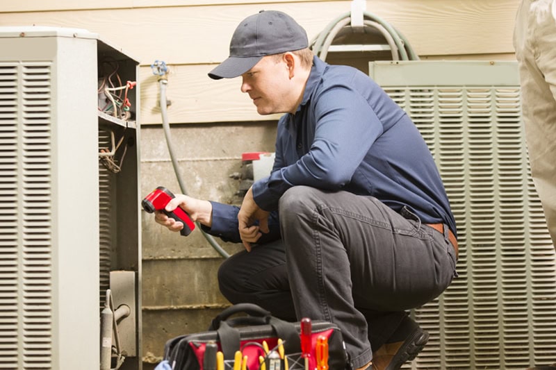 An HVAC maintenance person is checking the unit